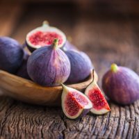 A few figs in a bowl on an old wooden background