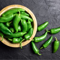 Green jalapeno hot pepper in wooden plate