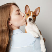 girl kissing her basenji pet