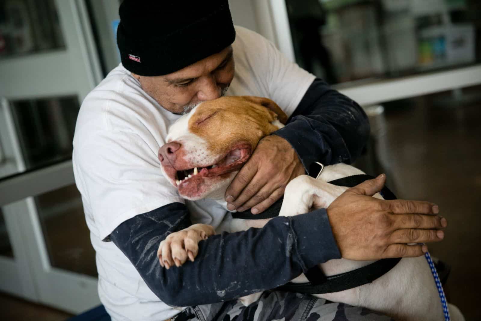 a man hugs and kisses his pit bull