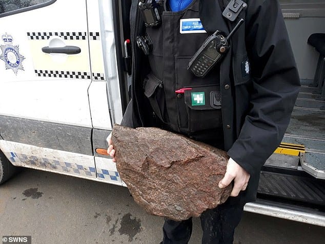 the policeman is holding a piece of rock in his hands