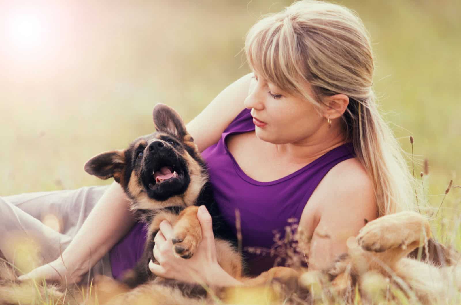 woman and german shepherd puppy lying in the grass