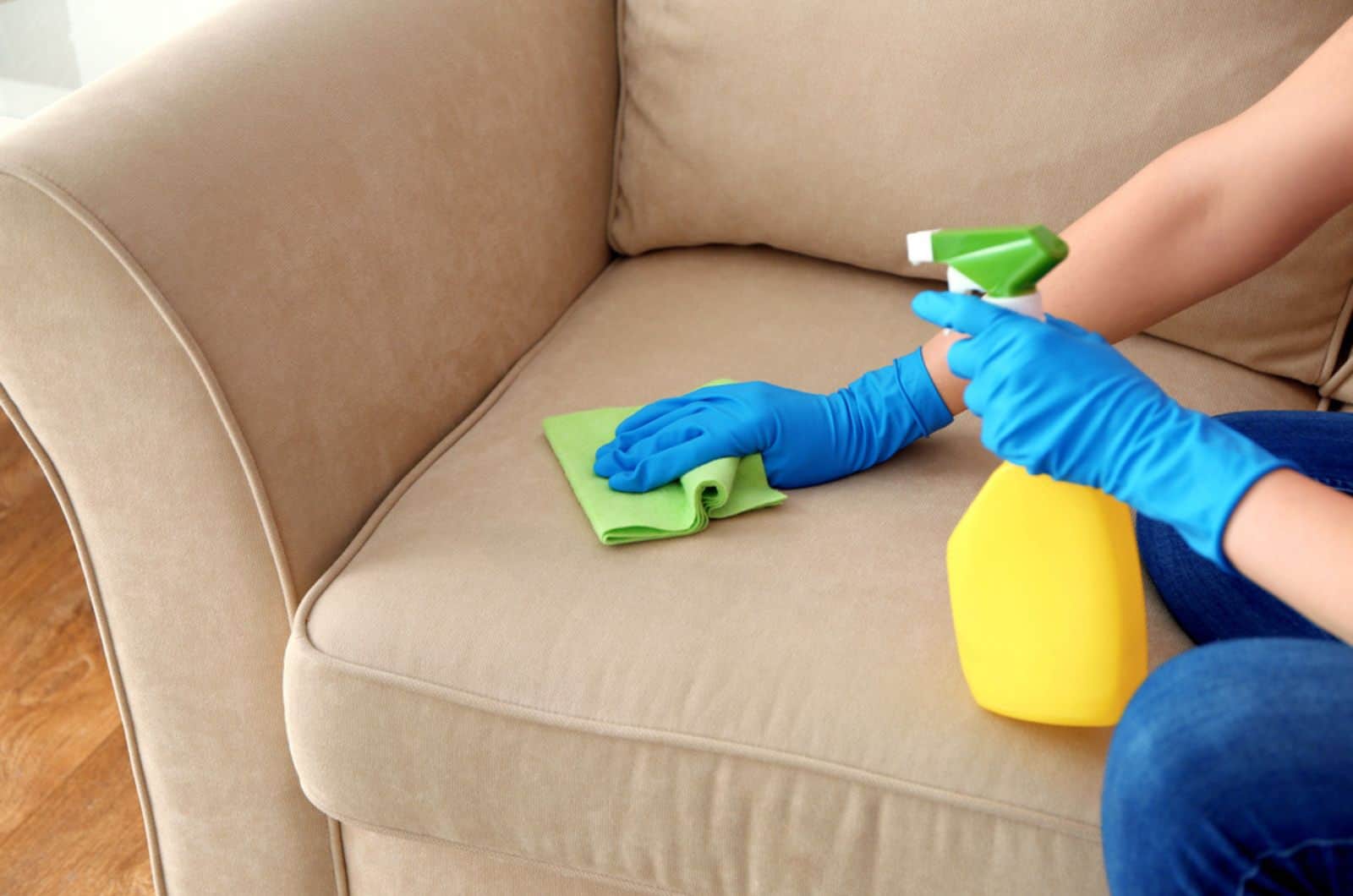 woman cleaning sofa with spray