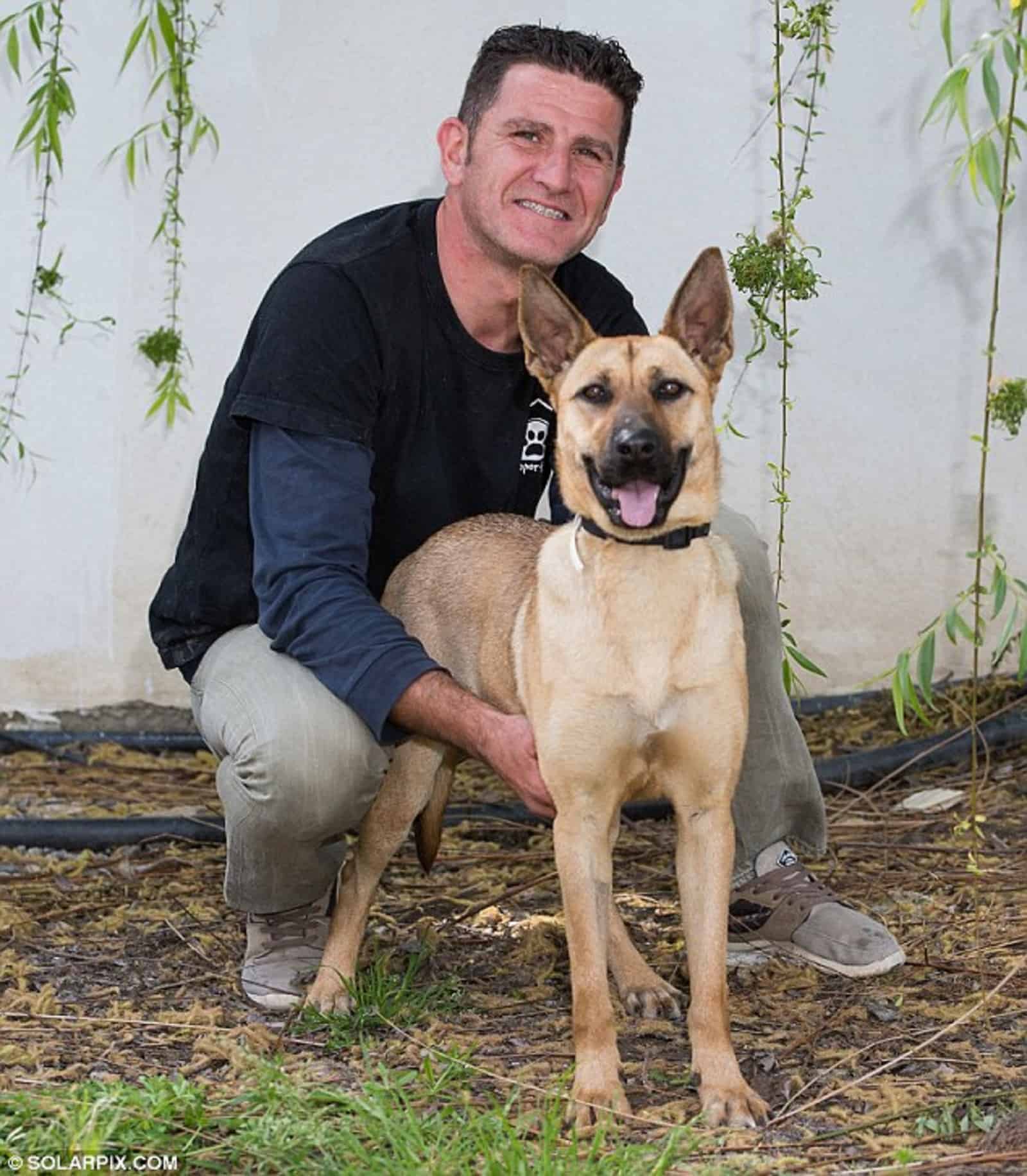 man hugging dog in the yard