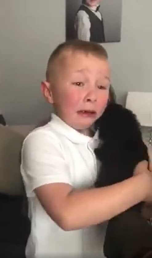 boy cries tears of happiness while holding a puppy
