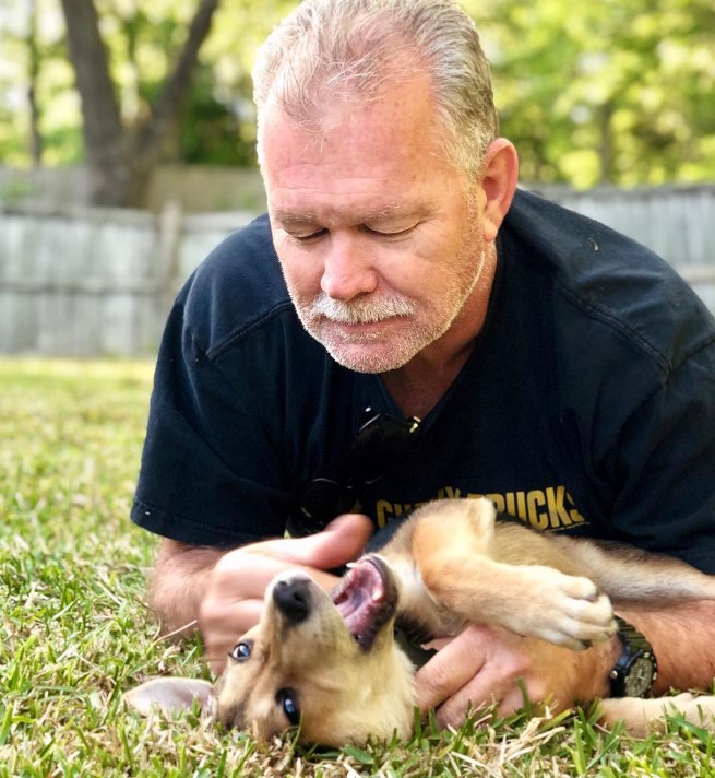 a man cuddles with a dog on the grass