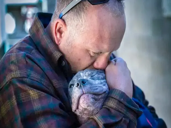a man holds a puppy in his arms and kisses it