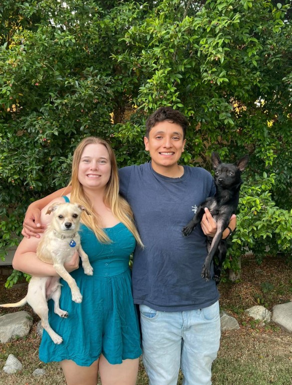 a man and a woman hold their dogs in their arms