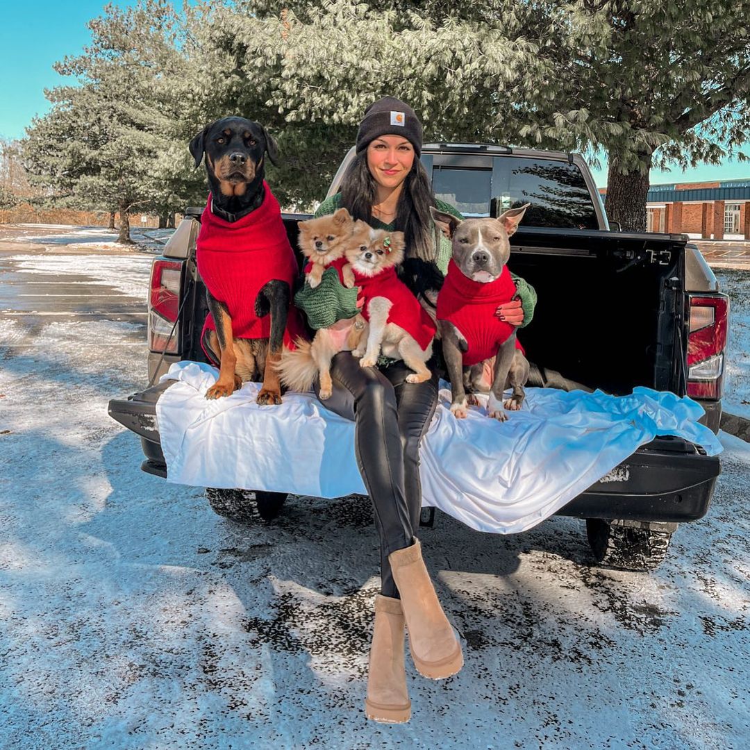 woman sitting in the back of the pickup with dogs