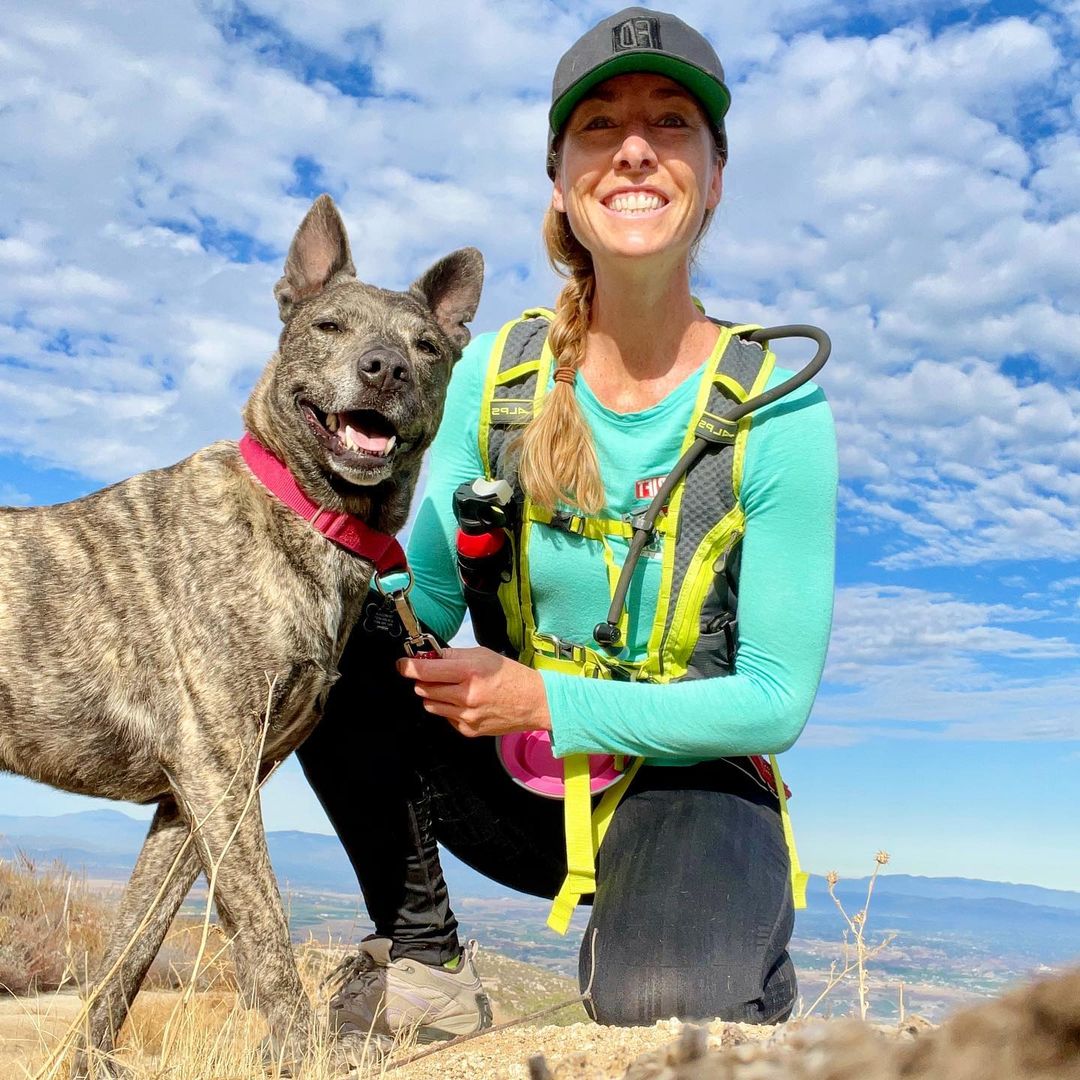 woman squatting next to a dog