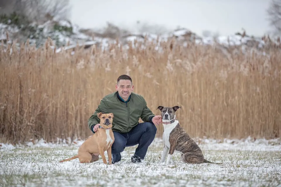 man posing with two dogs