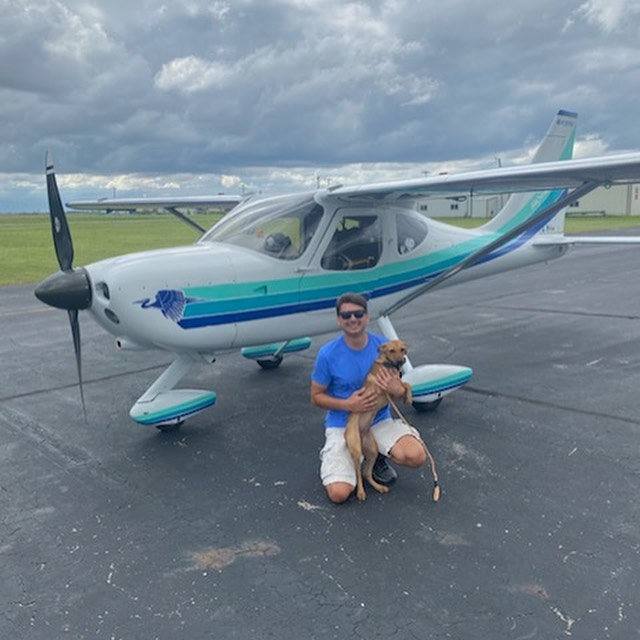 Guy holding dog near airplane
