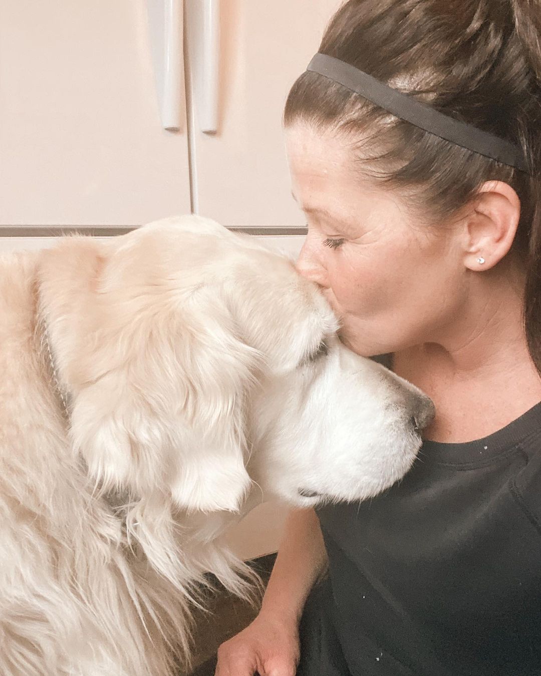 woman kissing white dog