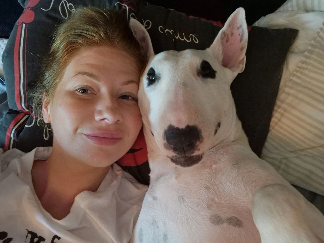 Woman and white dog laying together