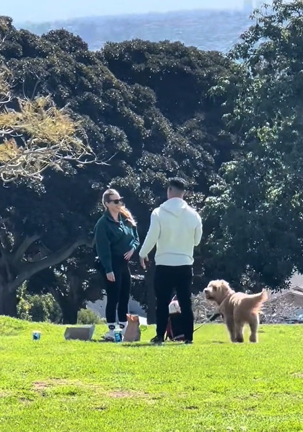 man standing with woman and dog in the park