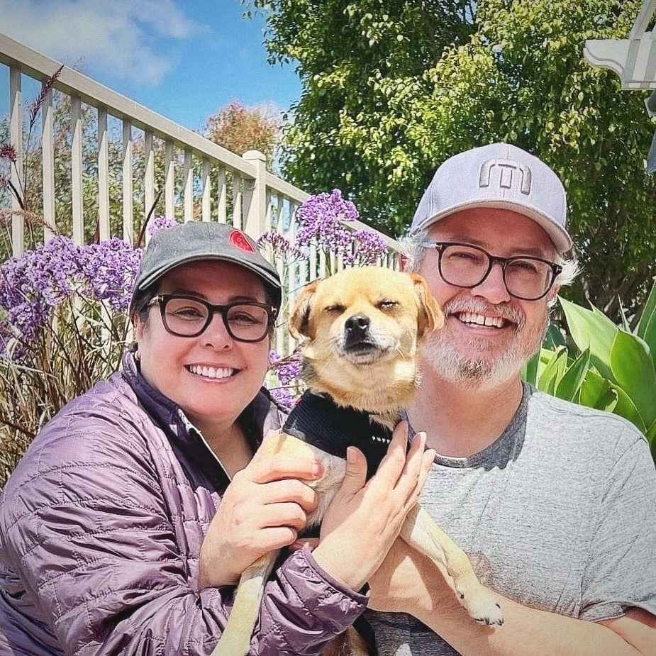 smiling couple posing with adopted dog