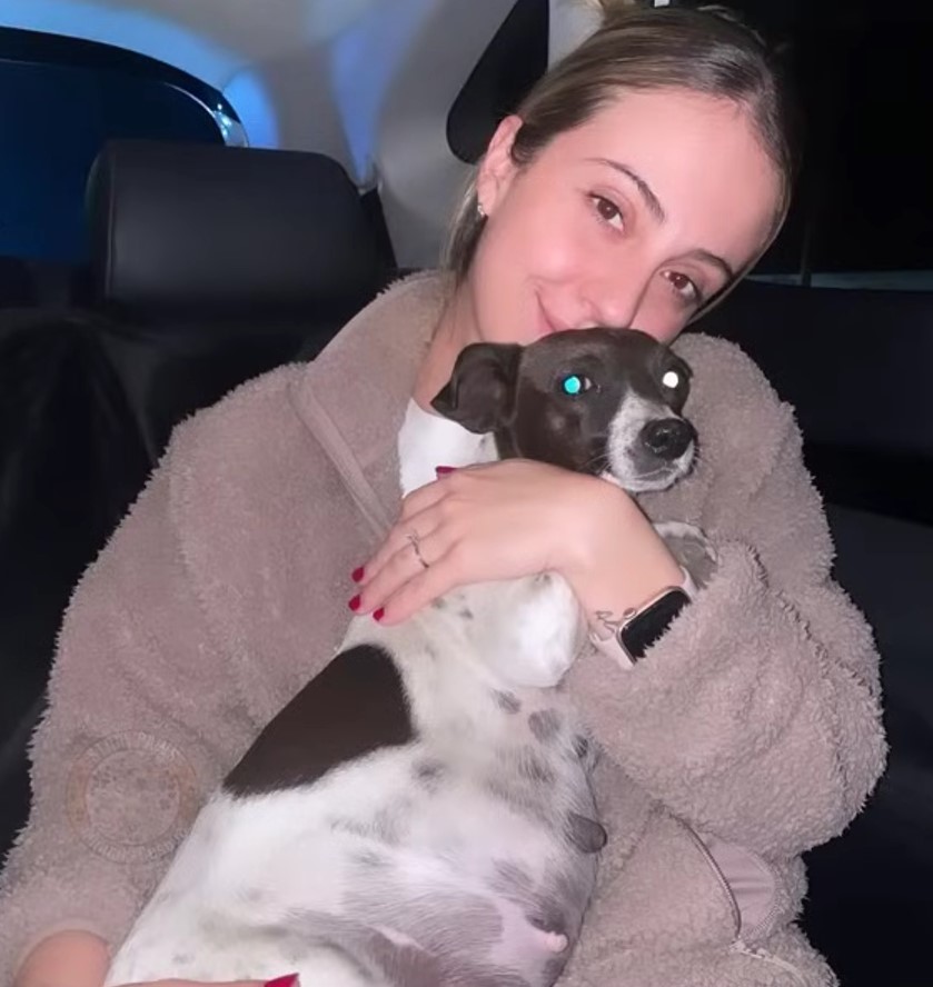 young woman holds a dog in the car