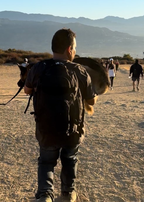 a mountaineer carries a German shepherd in his arms