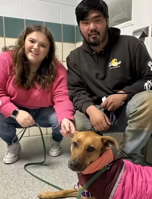 a man and a woman take a picture with a dog