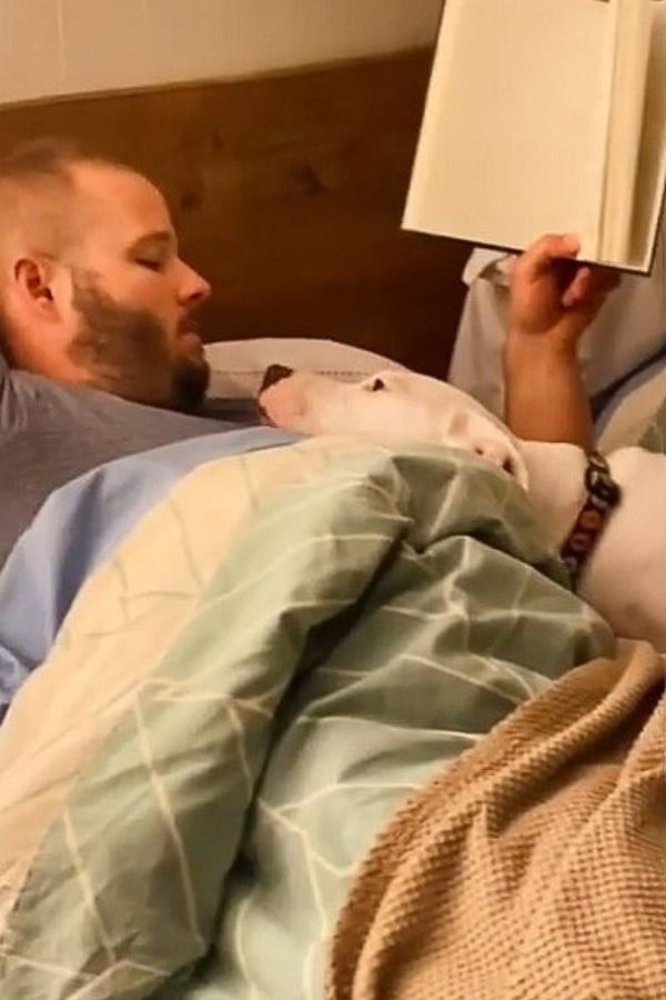 man and pup lying in bed