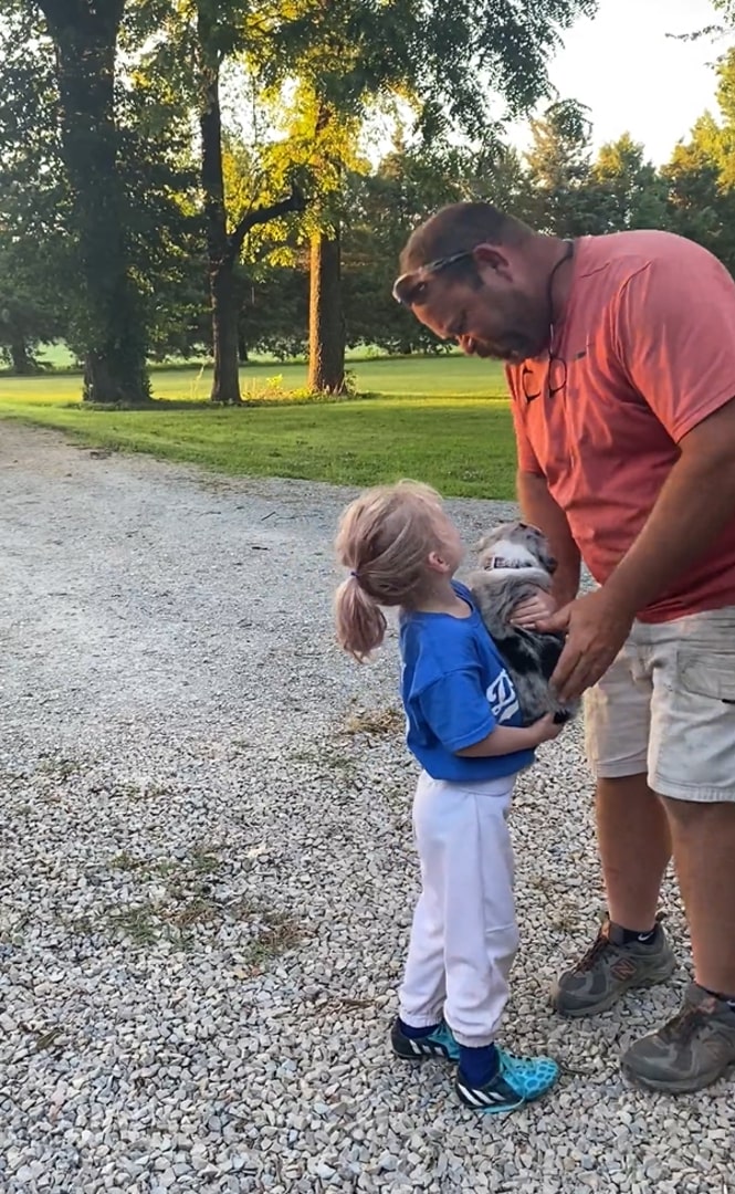 man giving puppy to little girl