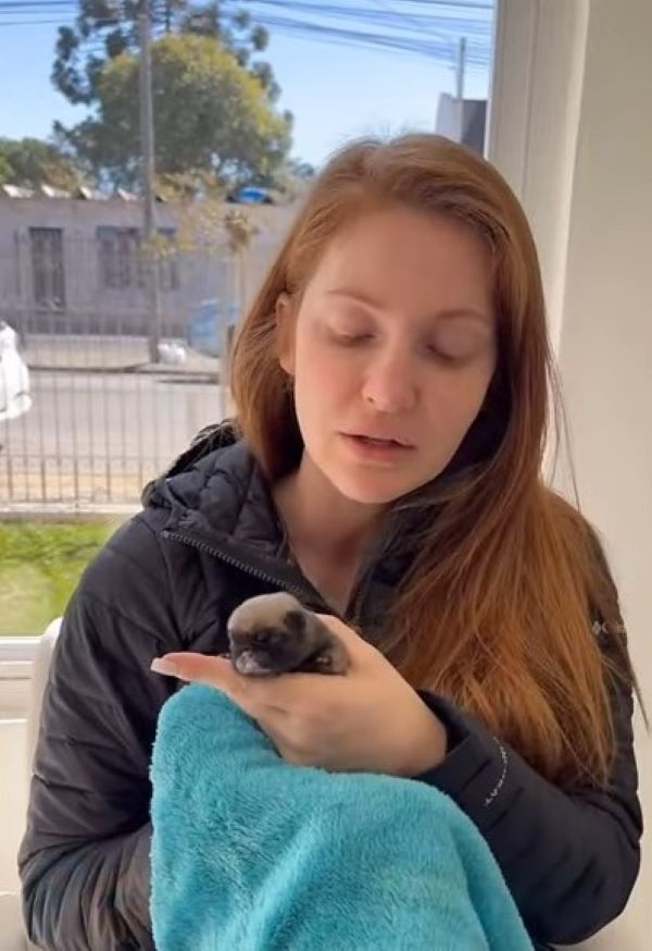 the girl is holding a newborn puppy in her arms