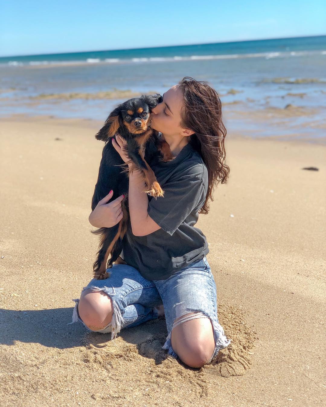 woman kissing a dog on a beach