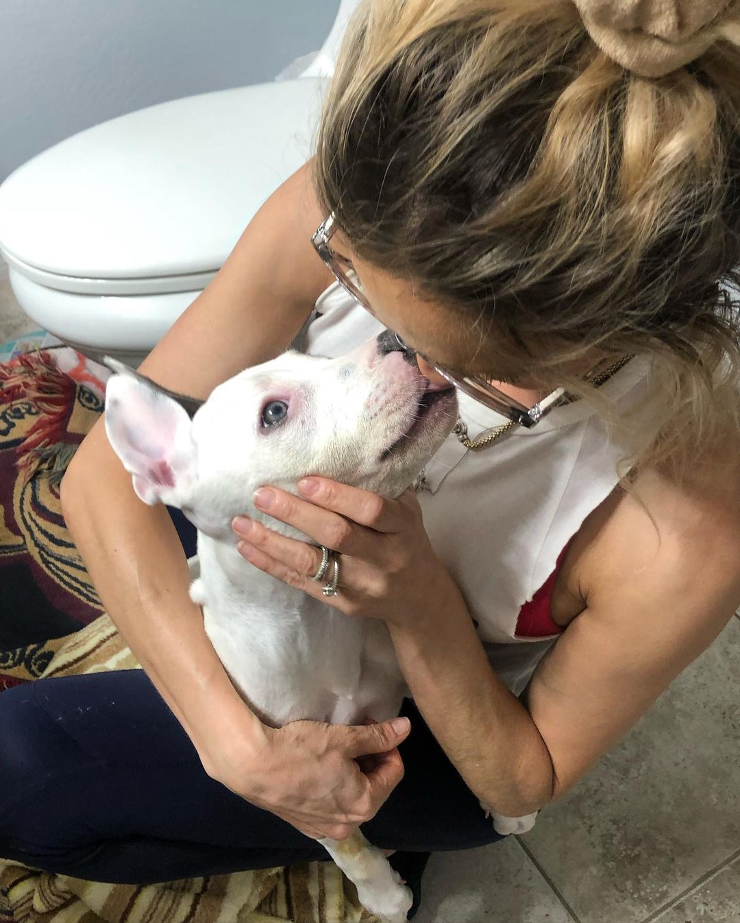 woman kissing dog in bathroom