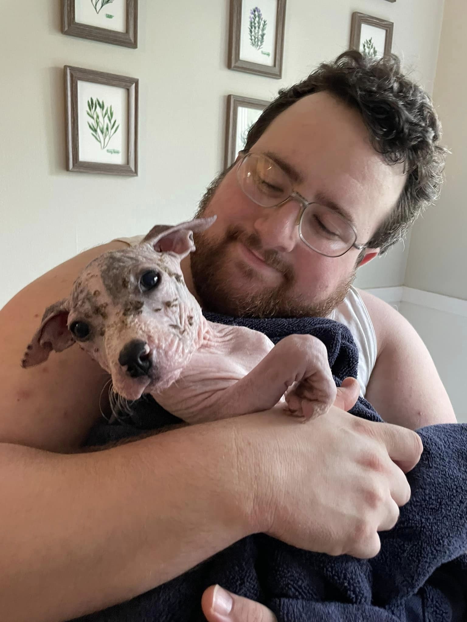 a man holds a bald dog in his arms