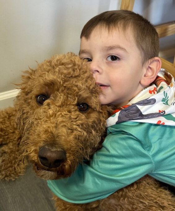 boy hugging goldendoodle