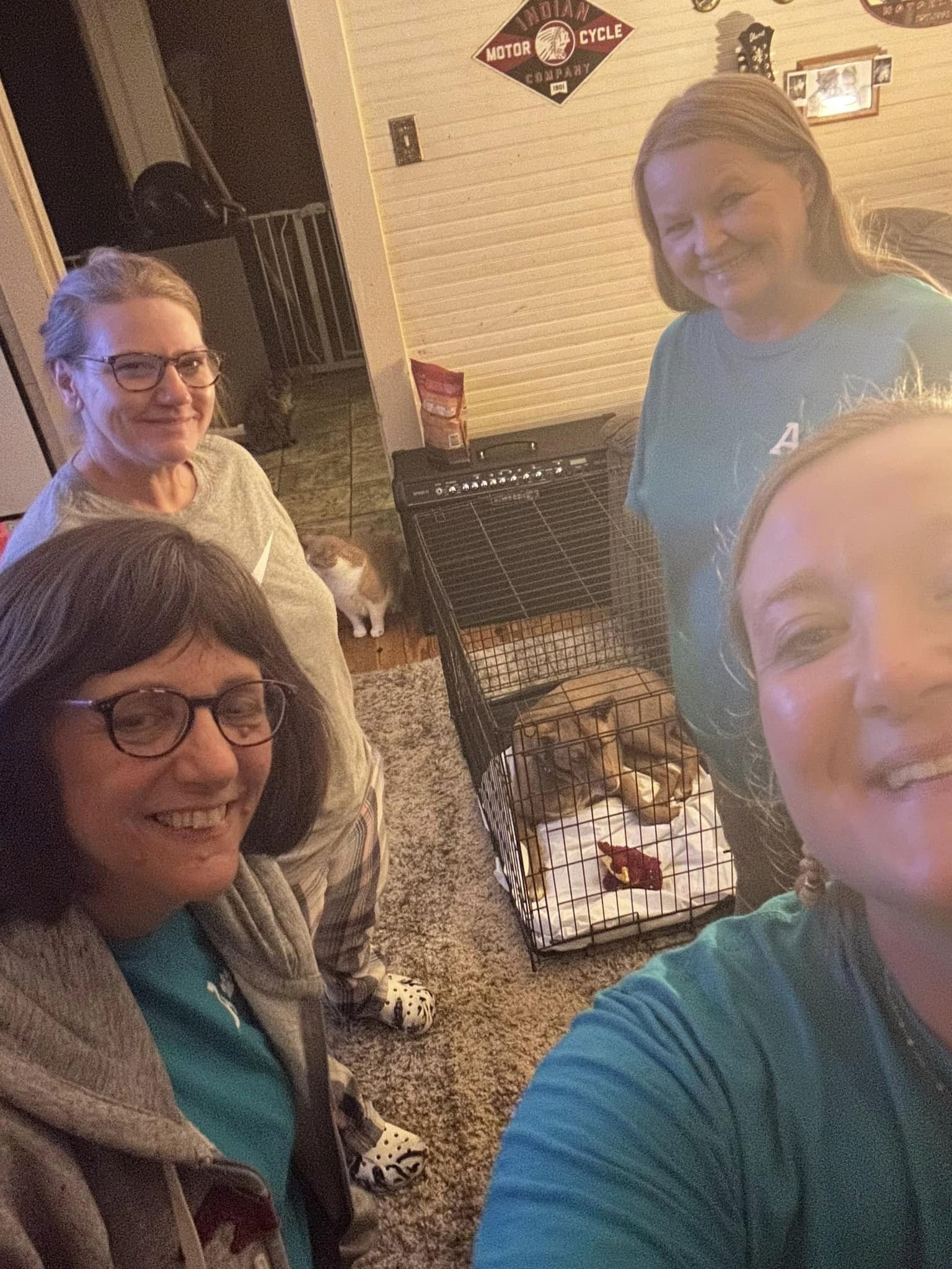 four women taking a selfie with dog in cage