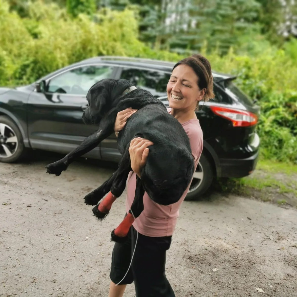 smiling girl carrying a black dog