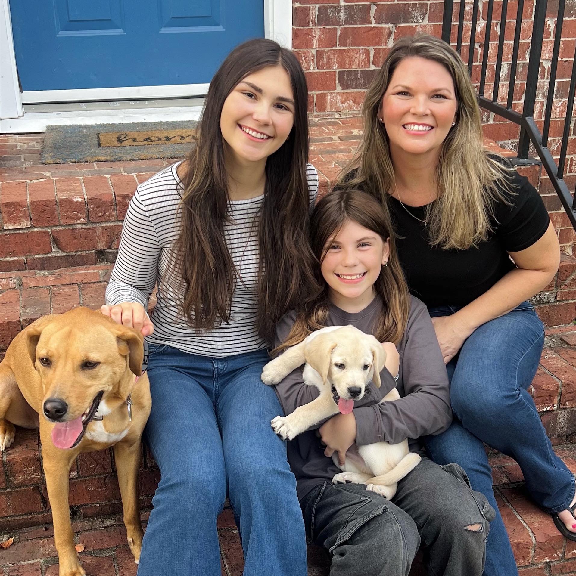 woman, two girls and two dogs sitting on stairs