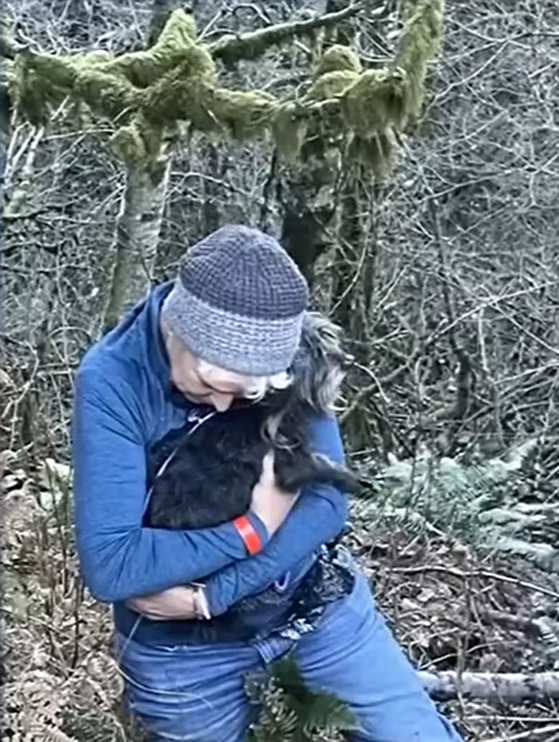 man hugging black dog