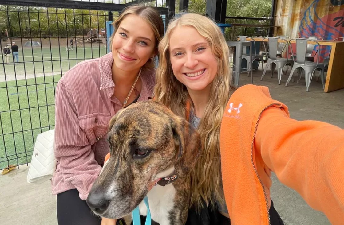 two girls taking a picture with a dog