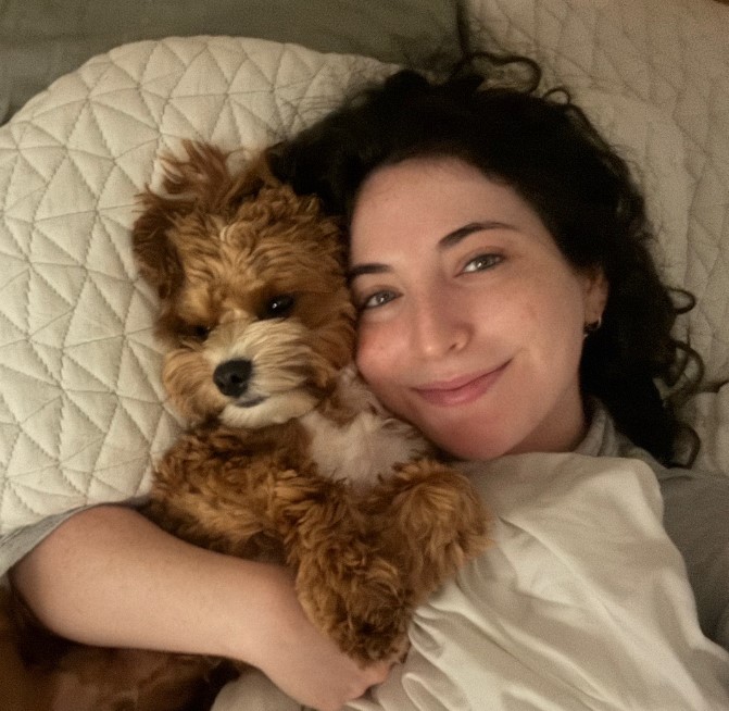 a girl takes a picture in bed with a brown dog