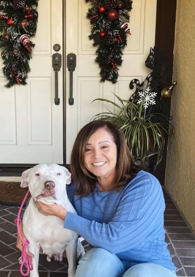 a woman takes a picture with a white dog