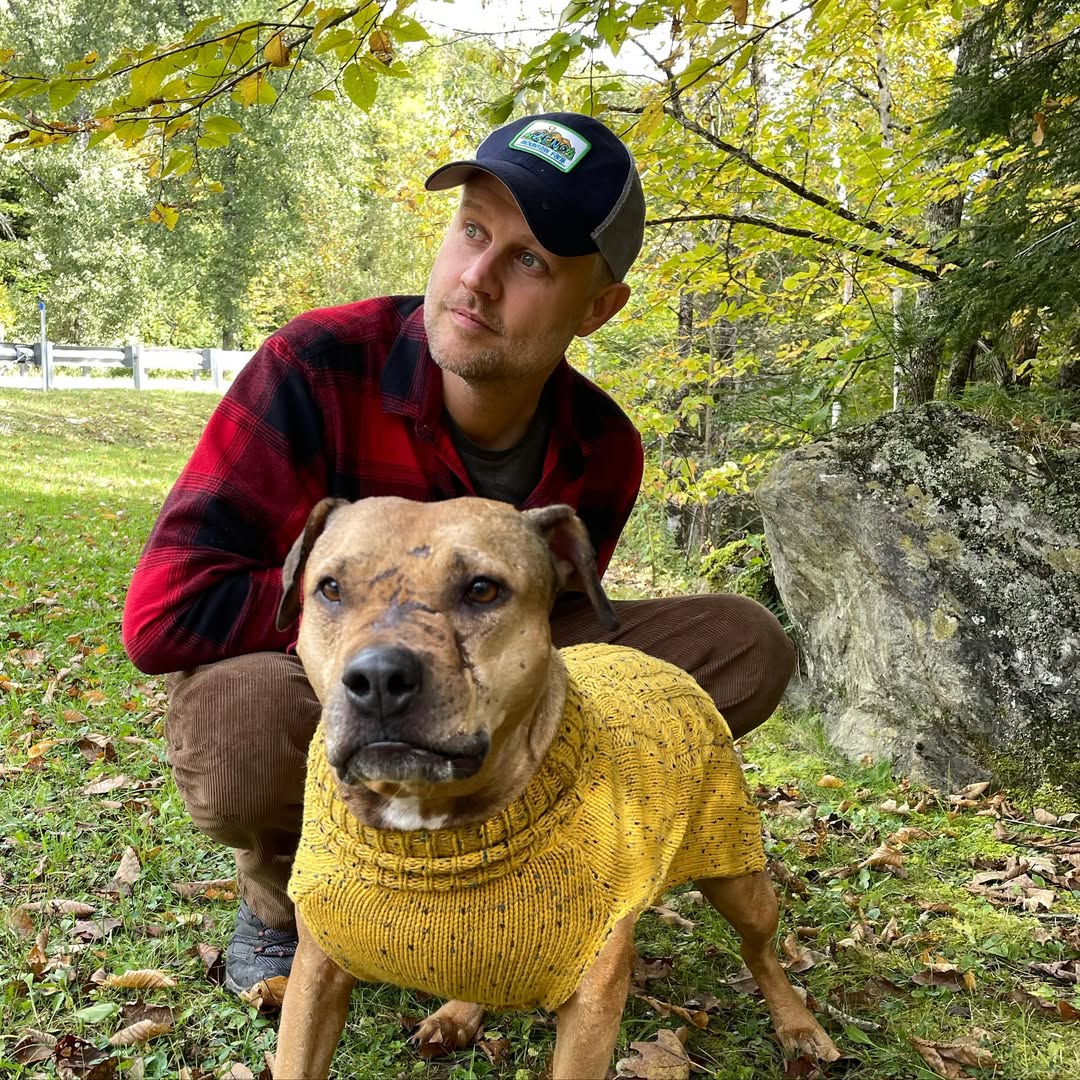 man standing with dog in yellow sweater