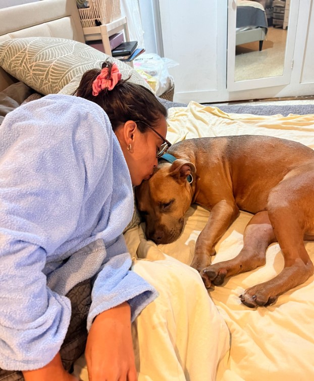 woman kissing a brown dog